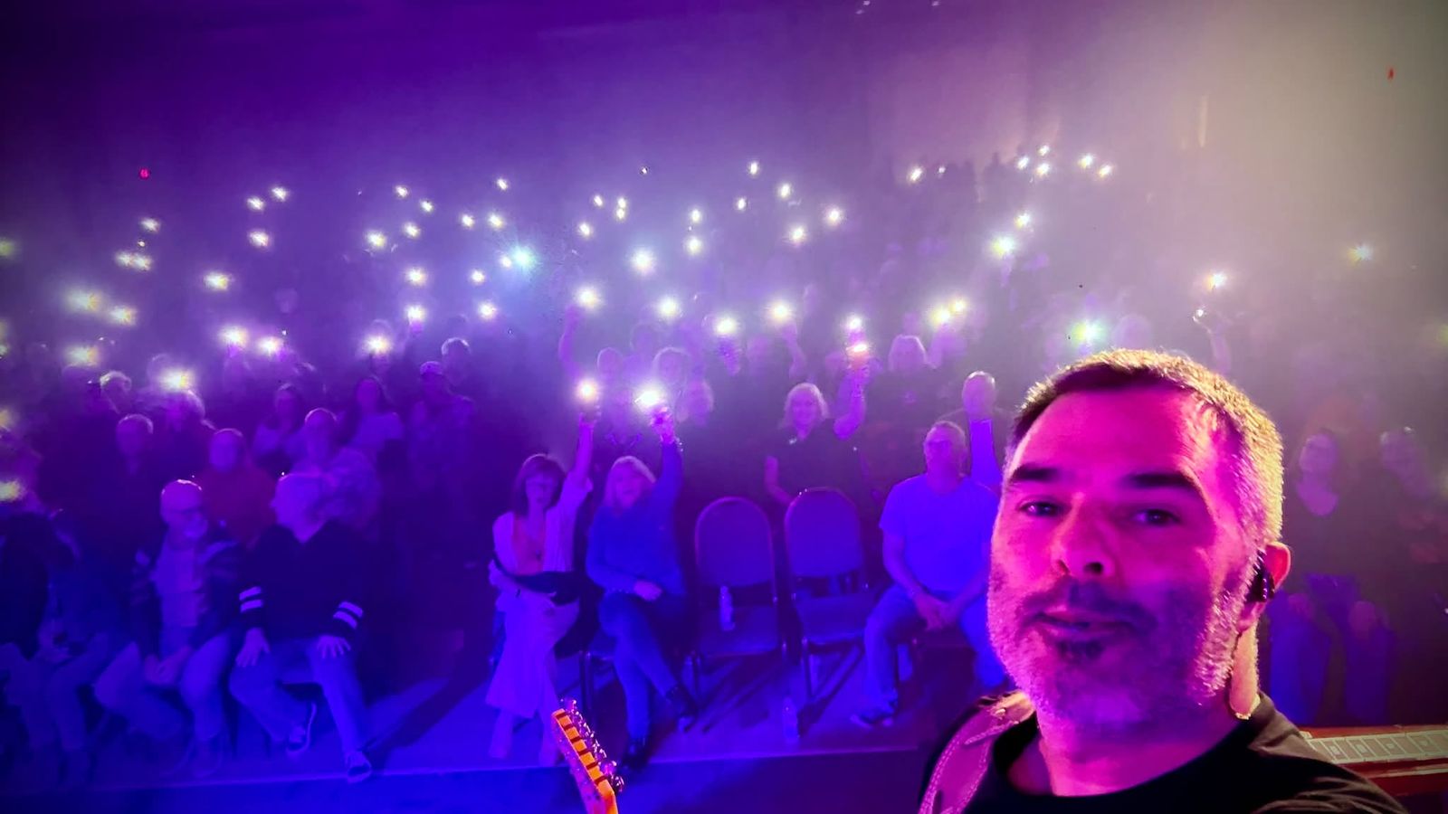 Crowd lit by phone lights during the show, a band member in the foreground, in Shawinigan