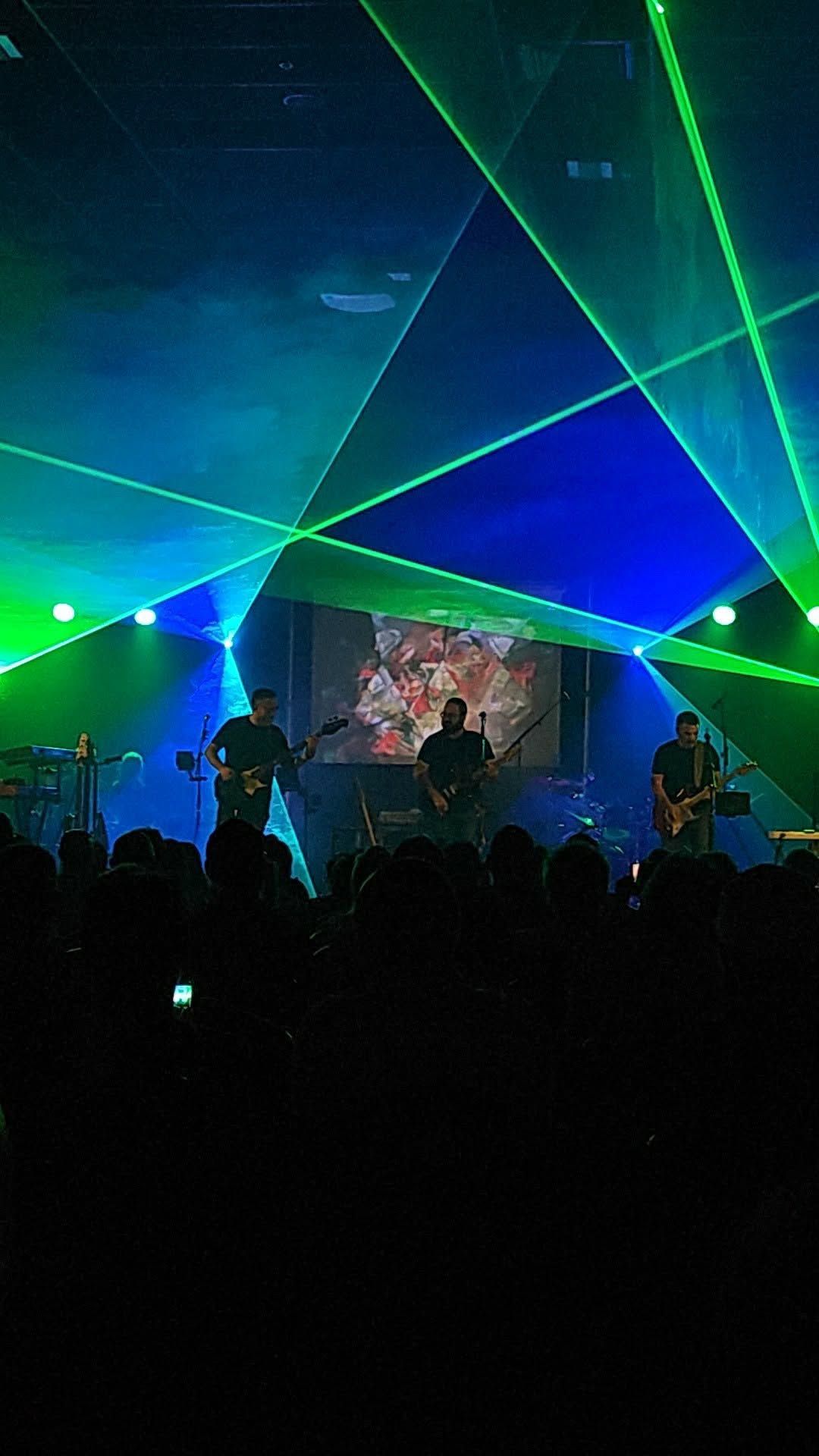 The band on stage with green lasers, in front of the crowd (vertical photo)